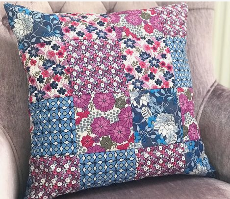 20 DIY Crafts With Old Clothes That Are Easy to Make A patchwork throw pillow sewn from colorful floral and geometric fabric scraps, showcasing creative DIY crafts with old clothes and textile recycling.