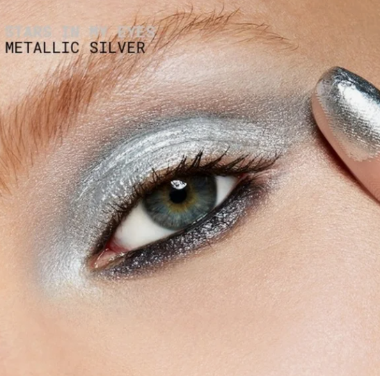 Close-up of an eye demonstrating which makeup look is trending now, featuring a futuristic metallic silver chrome eyeshadow application.