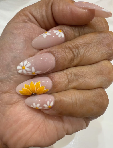 24 Sunflower Nail Ideas for a Bright, Cheerful Manicure sunflower nail ideas featuring almond-shaped nails with a sheer nude base, decorated with white daisy flowers and a standout accent nail featuring a vibrant yellow sunflower.