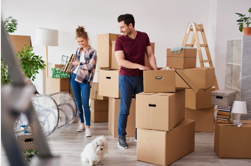 "Cozy home decor ideas for a small apartment featuring a couple unpacking cardboard moving boxes in their new home with their small dog."