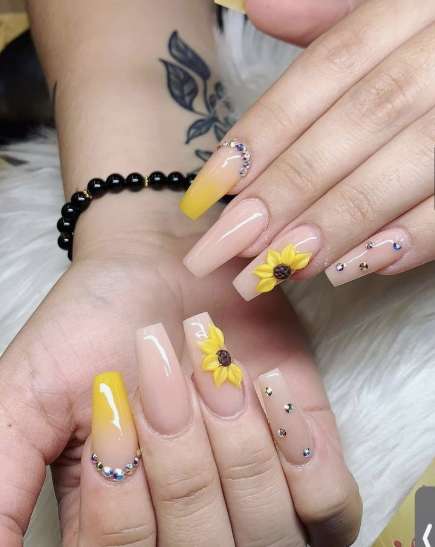 24 Sunflower Nail Ideas for a Bright, Cheerful Manicure sunflower nail ideas featuring long coffin-shaped nails with a nude base, complemented by ombre yellow gradient tips, 3D sculpted yellow sunflowers, and sparkling rhinestone gem embellishments.