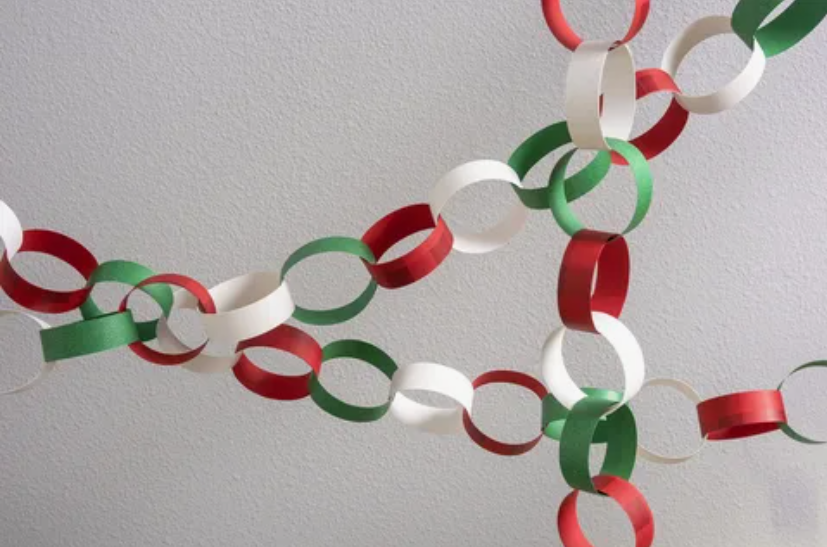 Interlocking paper loops in alternating colors of red, green, and white, forming decorative hanging chains against a light background.