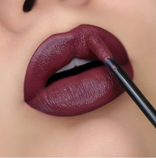Matte Lipstick Styles in 2026: Modern Looks, Shades & Easy Tips Close-up shot of lips being precisely lined with a dark berry shade using a liquid lipstick wand applicator, showcasing a rich matte finish.