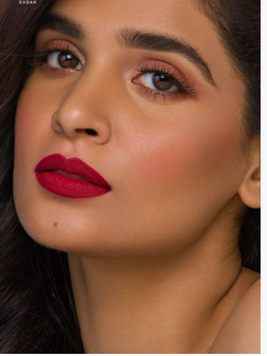 Matte Lipstick Styles in 2026: Modern Looks, Shades & Easy Tips Close-up of a woman with bold red matte lipstick and warm, neutral eyeshadow makeup.