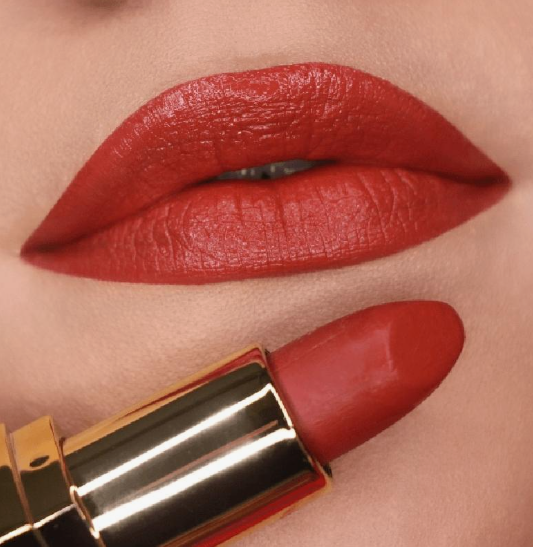 Matte Lipstick Styles in 2026: Modern Looks, Shades & Easy Tips Close-up of lips wearing a vibrant coral-red matte lipstick next to a matching lipstick bullet in a gold case.