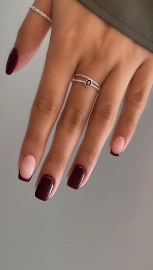 Creative burgundy nail designs featuring a mix of solid dark red square nails and delicate burgundy French tips on a nude base.