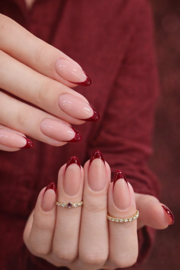 Sophisticated almond-shaped burgundy nail designs showcasing a modern twist on classic French tips with deep dark red arches on a neutral nude base.