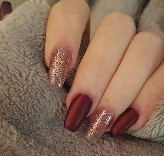 Elegant burgundy nail designs featuring a combination of solid matte dark red nails and shimmering rose gold or copper glitter accent fingers.