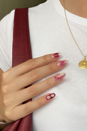 Artistic almond-shaped burgundy nail designs featuring unique translucent aura gradients, abstract tied-dye patterns, and delicate negative-space outlines