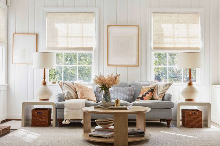 Vintage Modern Home Decor Ideas: 15 Ways to Mix Old and New "Bright living room showcasing Vintage Modern Home Decor Ideas, featuring a light gray tufted sofa, matching side tables with white lamps, natural wood accents, and framed artwork against white panel walls."