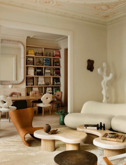 Vintage Modern Home Decor Ideas: 15 Ways to Mix Old and New "A contemporary living space highlighting Vintage Modern Home Decor Ideas, featuring organic curved white modular seating, abstract coffee tables, sculptural decor, and an adjoining dining area with a built-in bookshelf."