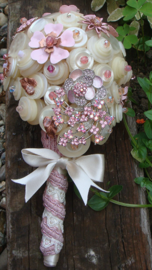 30 Creative DIY Button Crafts to Turn Spare Buttons Into Beautiful Decor A stunning wedding bouquet crafted from white and pink buttons, delicate fabric flowers, and sparkling crystal brooches, tied with a ribbon and lace handle, showcasing DIY button crafts.