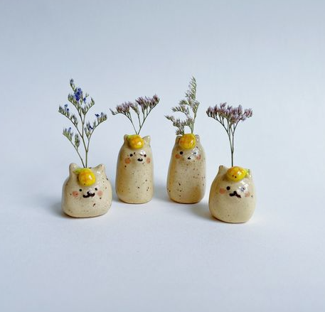 Four whimsical animal-shaped air dry clay crafts functioning as miniature bud vases, each speckled and holding sprigs of dried flowers.
