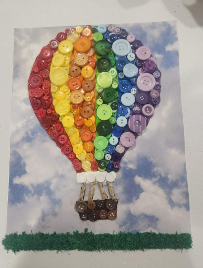 30 Creative DIY Button Crafts to Turn Spare Buttons Into Beautiful Decor A creative wall art print featuring a vibrant hot air balloon made of colorful stripes of buttons floating in a sky filled with clouds, highlighting DIY button crafts.