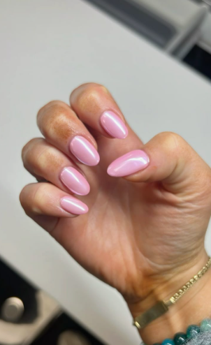 Short pink chrome nails with a glossy, pearlescent finish.