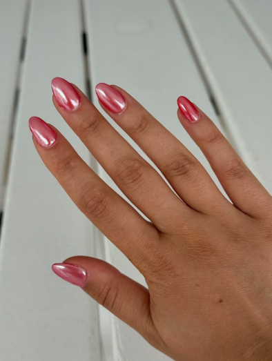Short almond-shaped pink chrome nails with a vibrant metallic and glossy finish.