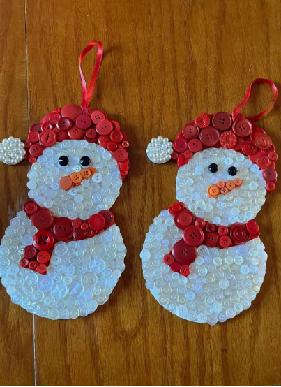 30 Creative DIY Button Crafts to Turn Spare Buttons Into Beautiful Decor Two festive holiday snowman ornaments made from white and pearl buttons, wearing red button hats and scarves, hanging by red ribbon loops, highlighting DIY button crafts.