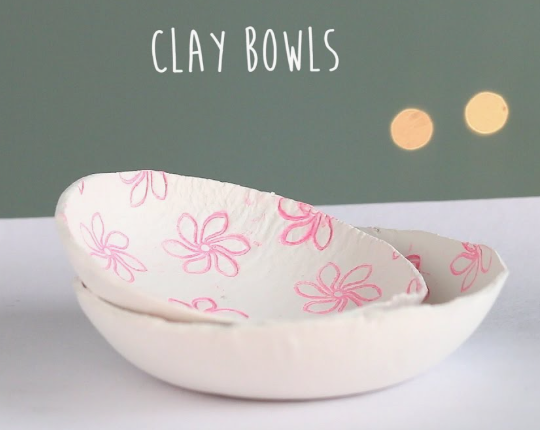 Two stacked handmade white clay bowls decorated with stamped pink floral patterns, showcasing simple air dry clay ideas for custom trinket dishes.