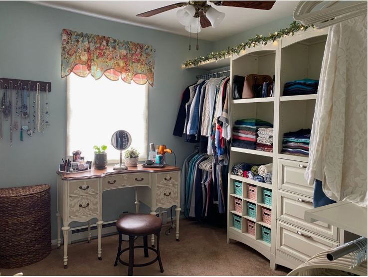 Small bedroom idea with no closet featuring an open wardrobe system with clothing racks and shelving units alongside a vintage vanity desk and wall-mounted jewelry organization.