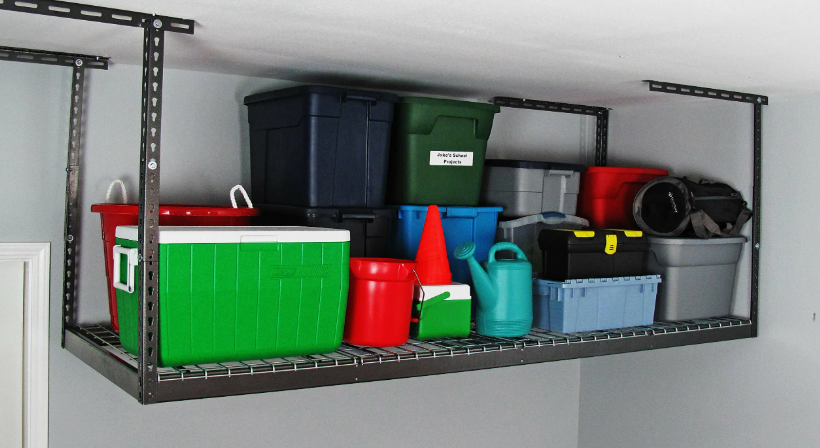 Small bedroom idea with no closet featuring an overhead ceiling storage rack mounted with heavy-duty metal brackets and loaded with plastic storage bins, containers, and gear.