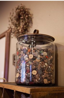 30 Creative DIY Button Crafts to Turn Spare Buttons Into Beautiful Decor A large glass jar filled to the brim with a massive collection of assorted buttons, sitting on a shelf as part of home decor, highlighting DIY button crafts.