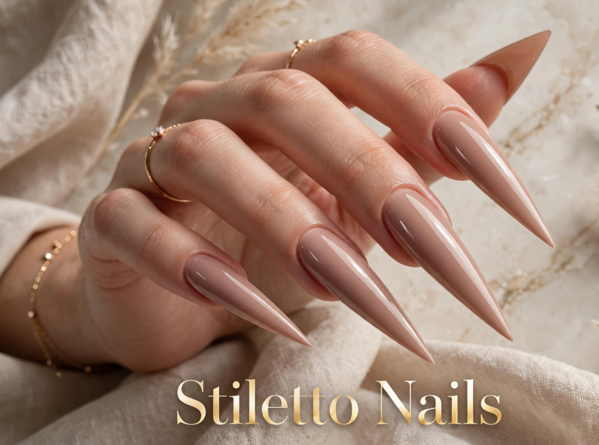 Close-up of stiletto style nails featuring long, dramatically pointed nails in a glossy taupe nude finish, overlaid with the title "Stiletto Nails".   