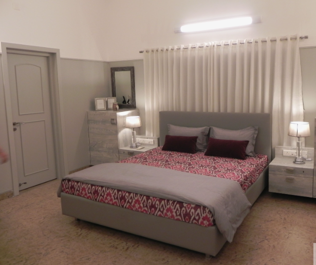 Small Bedroom Layout Ideas: How to Arrange Furniture in a Tiny Room Small bedroom layout idea featuring a central gray upholstered bed with patterned bedding, flanked by matching nightstands and a dresser beneath a window with white curtains.