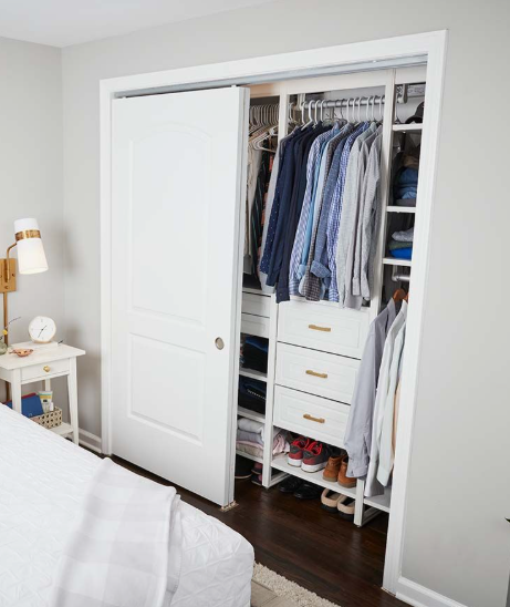 Small Bedroom Layout Ideas: How to Arrange Furniture in a Tiny Room Small bedroom layout idea featuring a built-in closet with sliding doors, organized hanging racks, drawers, and shelving next to a compact nightstand and bed.