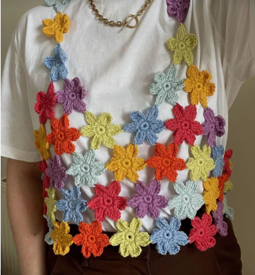 A colorful crocheted top made from joined floral motifs worn layered over a white t-shirt, featured as one of 15 Crochet Upcycle Ideas.