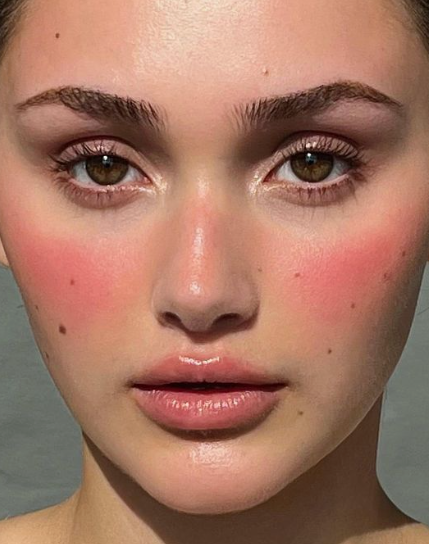 Close-up portrait of a model with flushed pink cheeks and glossy lips capturing Fall 2026 Beauty Trends.