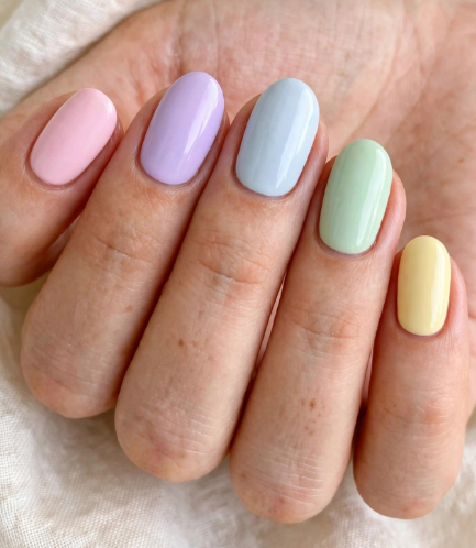 Easy pastel skittle nail art for beginners featuring glossy pink, lavender, baby blue, mint green, and pale yellow oval nails.   