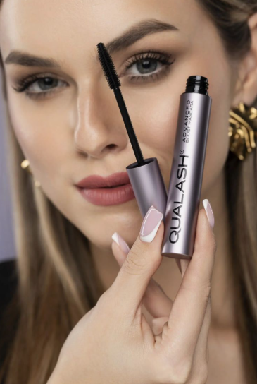 Model holding a tube of Qualash Advanced Boost Mascara to showcase volumized eyelashes fitting into Fall 2026 Beauty Trends.