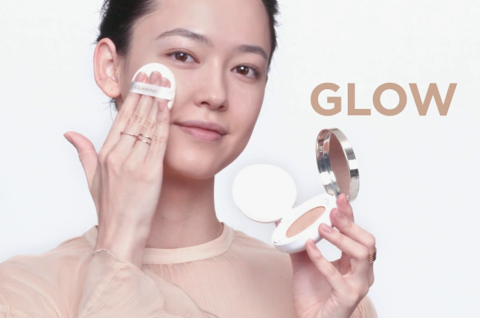 Low Maintenance Beauty Routine: A Simple 5-, 10-, and 15-Minute System A woman applying a lightweight cushion foundation to her face as part of a low maintenance beauty routine, with the word 'GLOW' displayed on the side.