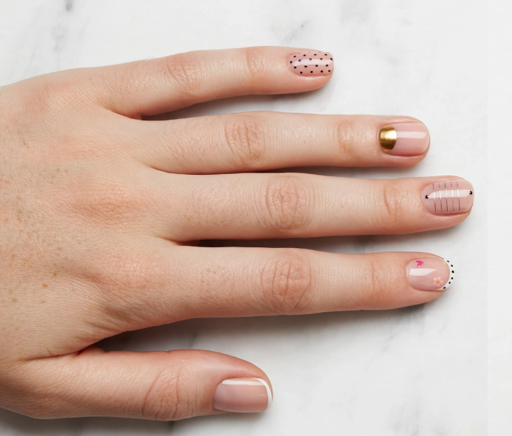 Mix-and-match minimalist nail art with regular polish featuring gold foil, polka dots, fine lines, and French tips on sheer nude short nails.   