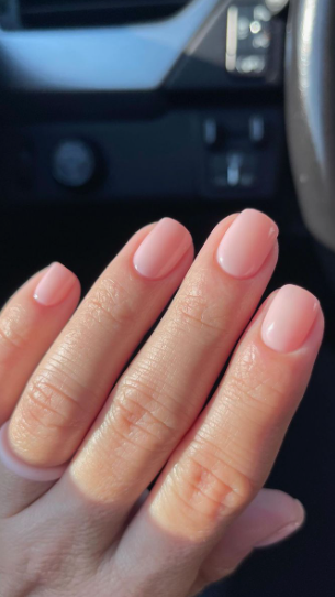 Low Maintenance Beauty Routine: A Simple 5-, 10-, and 15-Minute System A close-up shot of short, neatly manicured square nails painted in a sheer milky pink polish, representing a clean and effortless look for a low maintenance beauty routine.