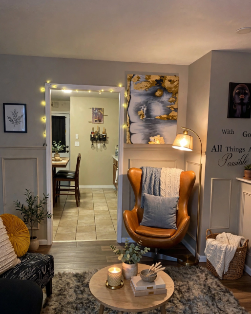 Luxury home decor on a budget featuring a cozy reading corner with a cognac leather egg chair, brass floor lamp, textured rug, and modern wall art.