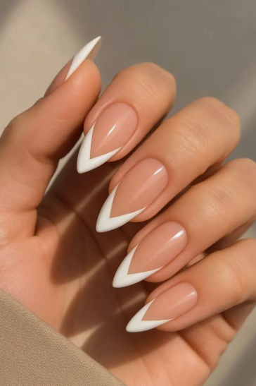 35 Short Nail Designs That Make Your Fingers Look Longer A close-up of short nails featuring a sharp V-shaped white French tip on a sheer base, serving as one of the short nail designs that make your fingers look longer.