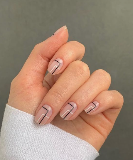 35 Short Nail Designs That Make Your Fingers Look Longer A close-up of short, rounded nails featuring minimalist geometric black and white line art on a neutral base, serving as one of the short nail designs that make your fingers look longer.