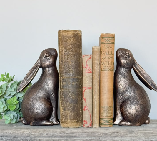 A stack of vintage books held together by bronze bunny bookends showcasing clever air dry clay ideas for home decor.