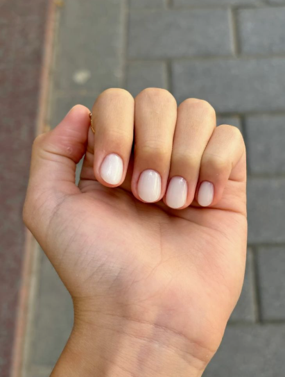 35 Short Nail Designs That Make Your Fingers Look Longer A close-up of short, rounded nails painted in an opaque milky white polish, serving as one of the short nail designs that make your fingers look longer.