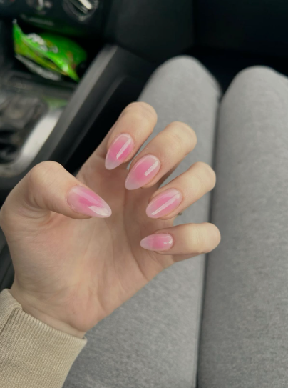 35 Short Nail Designs That Make Your Fingers Look Longer A close-up of short, almond-shaped nails featuring a trendy pink blush nail art effect on a sheer base, serving as one of the short nail designs that make your fingers look longer.