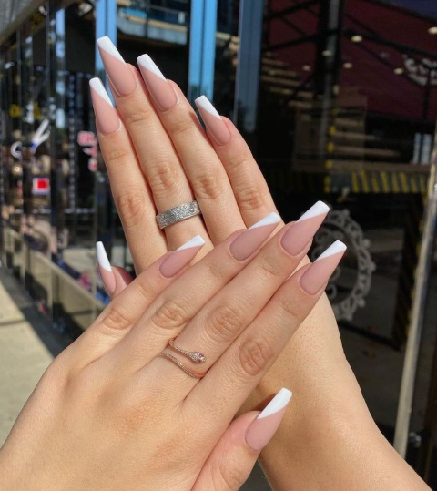 35 Short Nail Designs That Make Your Fingers Look Longer A close-up of long coffin-shaped nails with a diagonal white French tip on a nude base, representing a longer variation compared to short nail designs that make your fingers look longer.