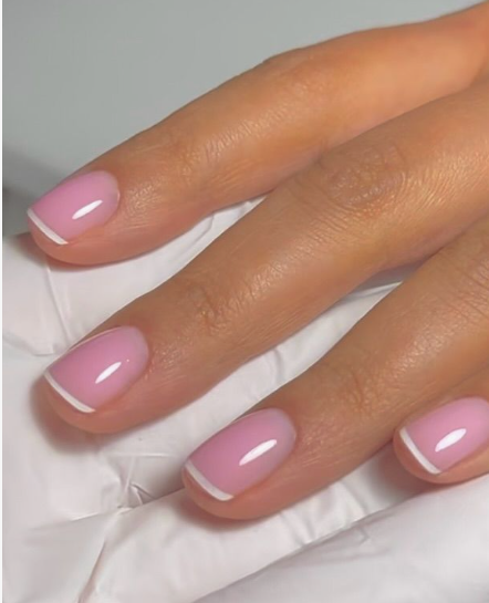 35 Short Nail Designs That Make Your Fingers Look Longer A close-up of short, squared-oval nails featuring an ultra-thin white French tip on a soft pink base, serving as one of the short nail designs that make your fingers look longer.