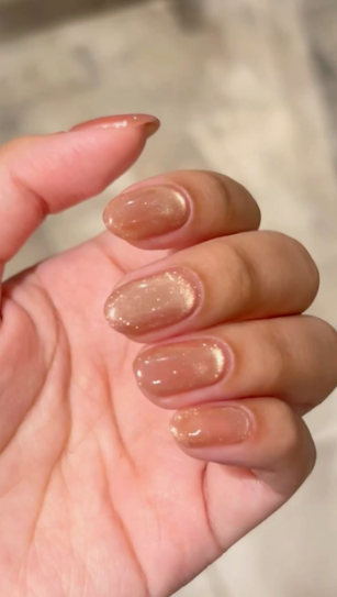 35 Short Nail Designs That Make Your Fingers Look Longer A close-up of short, rounded nails finished in a glossy, shimmering cat-eye gold and bronze polish, acting as one of the short nail designs that make your fingers look longer.