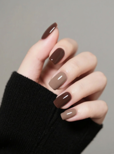 35 Short Nail Designs That Make Your Fingers Look Longer A close-up of short, square nails featuring alternating glossy espresso brown and caramel taupe tones, serving as one of the short nail designs that make your fingers look longer.