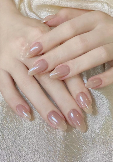 35 Short Nail Designs That Make Your Fingers Look Longer A close-up of short, oval-shaped nails featuring a glossy pearlescent glaze over a sheer neutral base, serving as one of the short nail designs that make your fingers look longer.