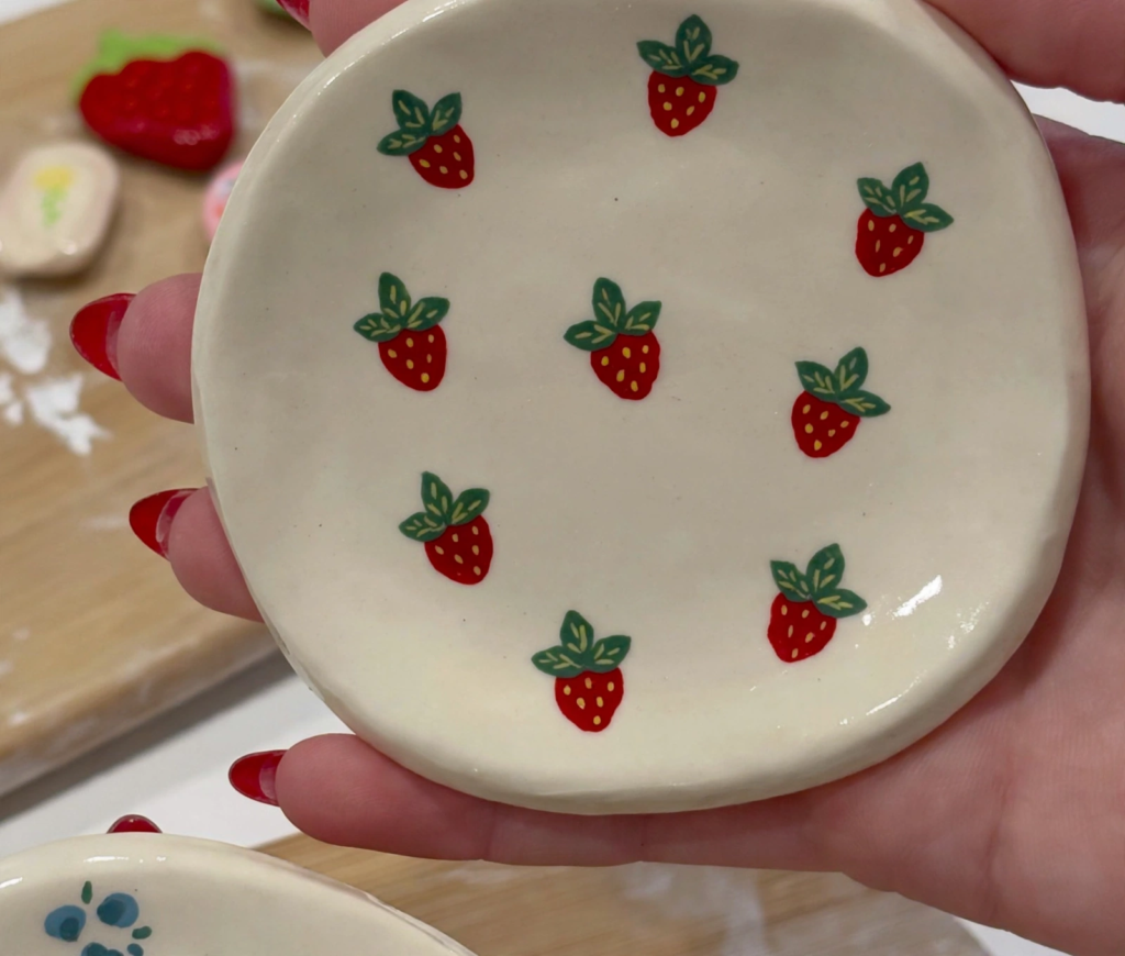 Handmade round clay trinket dish painted with cute red strawberries, showcasing easy craft ideas for teens[cite: 10].