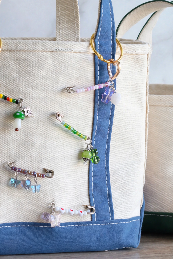 25 Craft Ideas for Teens That Are Actually Cool Handmade beaded safety pin charms decorating a canvas tote bag, showcasing easy craft ideas for teens