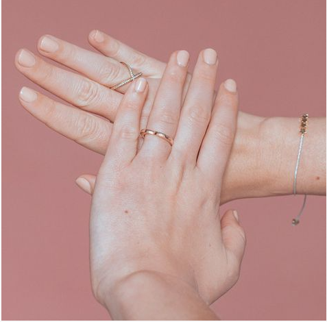 35 Short Nail Designs That Make Your Fingers Look Longer A close-up of short, square-rounded nails finished in a glossy, solid pale nude-beige polish, acting as one of the short nail designs that make your fingers look longer.