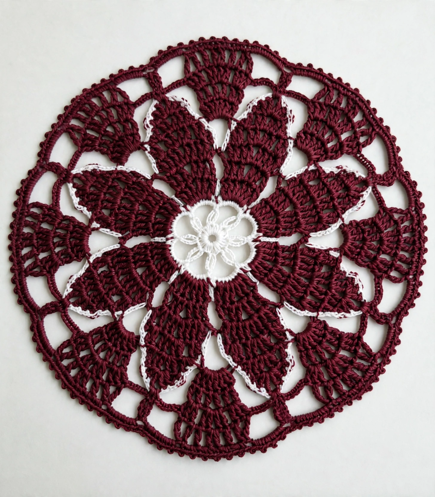 20 Nostalgic Crafts Making a Comeback in 2026 A handcrafted maroon and white circular crochet doily with intricate floral lace patterns, showcasing nostalgic crafts 2026 home decor trends on a plain white background.